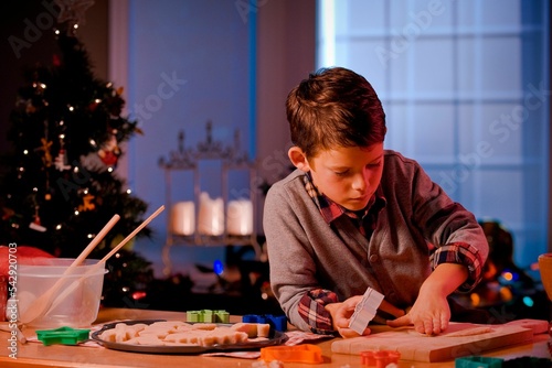 Little Caucasian boy making Christmas cookies with shapes