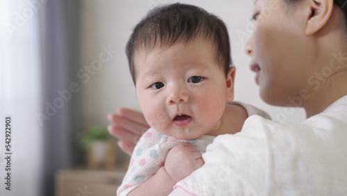 Tablou pe pânză close up shot adorable baby girl in her mom’s arms is getting little upset while being burped and patted on the back at home