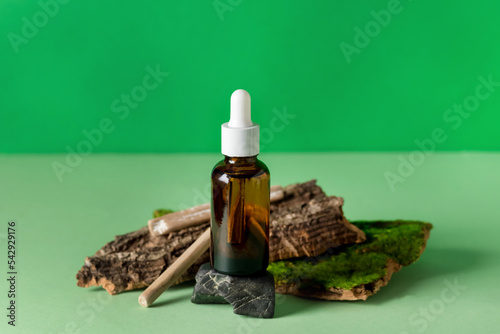 Serum Glass Bottle Green Background Composition with Natural Materials: Tree Bark, Stones Wooden Sticks Health and Natural Care Cosmetics Concept