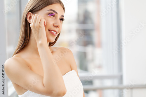 Woman doing morning makeup routine putting mascara in bathroom mirror at home Free Download Woman doing morning makeup routine putting mascara in bathroom mirror at home - GFXLoad