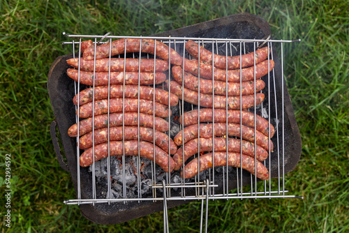 Cooking  sausages on the charcoal grill outdoor, Italy. Traditional BBQ with griends outdoor photo