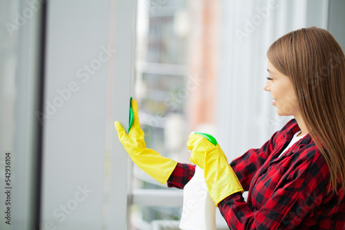 Young asian woman washing window with sponge.