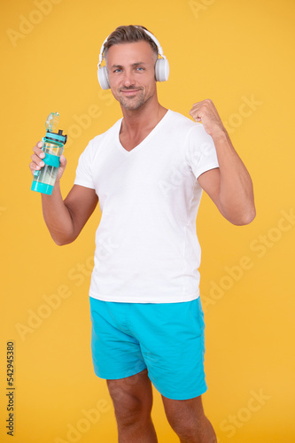 successful sporty man in headphones hold water bottle. sporty man with water bottle