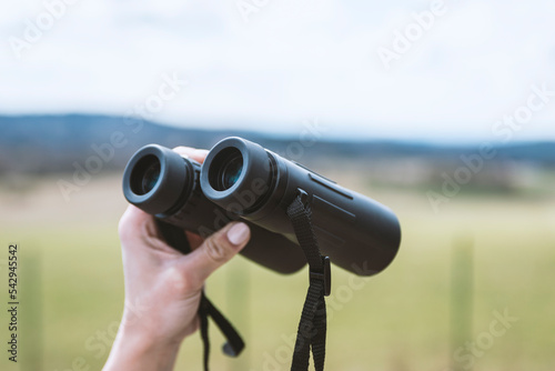 female hand holding a binoculars . © vigenmnoyan