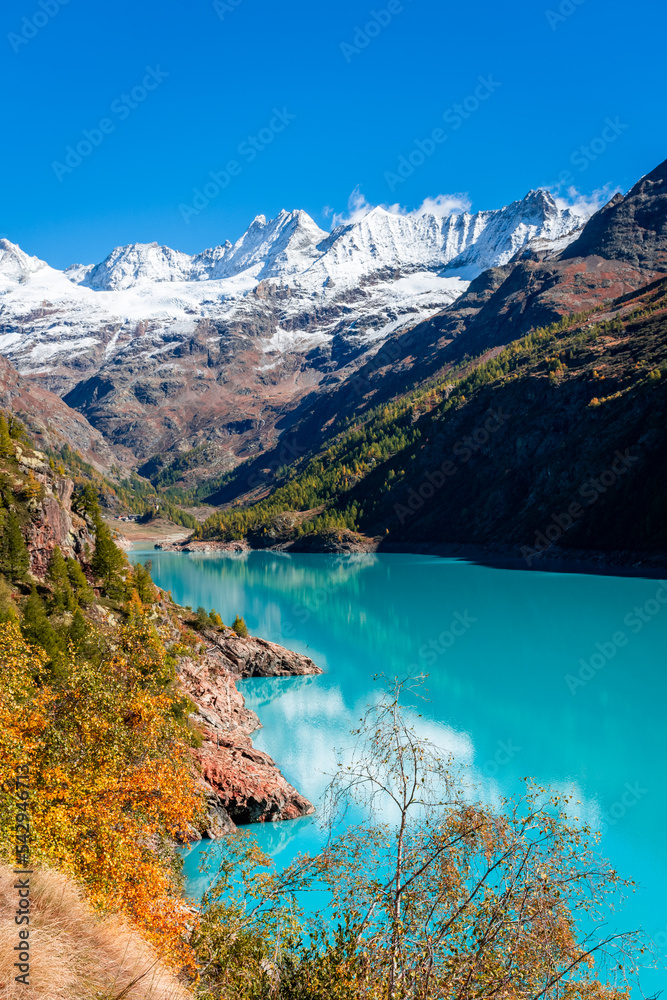 Autumnal landscape of the Lake Place Moulin, an artificial glacial lake with turquoise water in the italian Alps,  on the border with Switzerland
