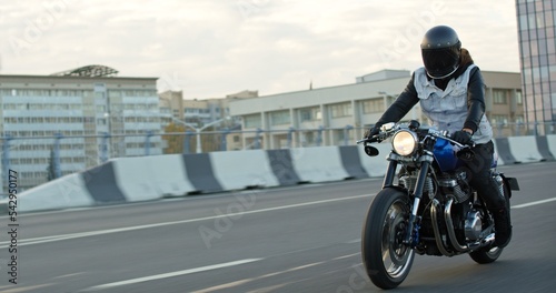 Man Driving Bike on Streets. Speed Motion in Cityscape. Fast TRACKING Shot of a biker riding his custom built cafe racer through city. Motorcyclist Drives on Motorcycle on Road