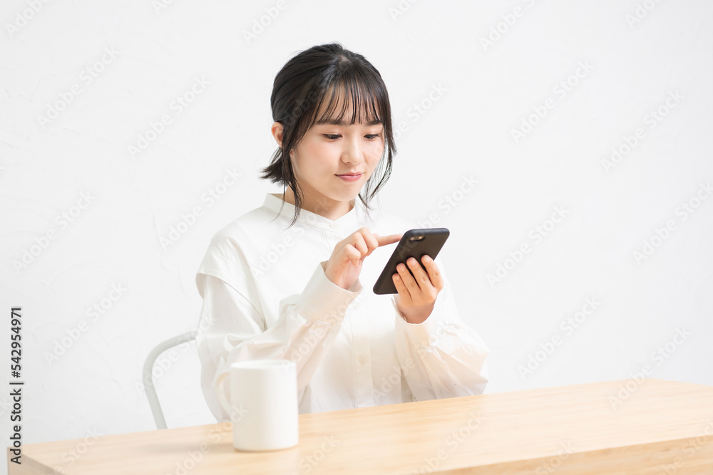 椅子に座ってスマホを使っている若い女性 椅子に座ってスマホを使っている若い女性