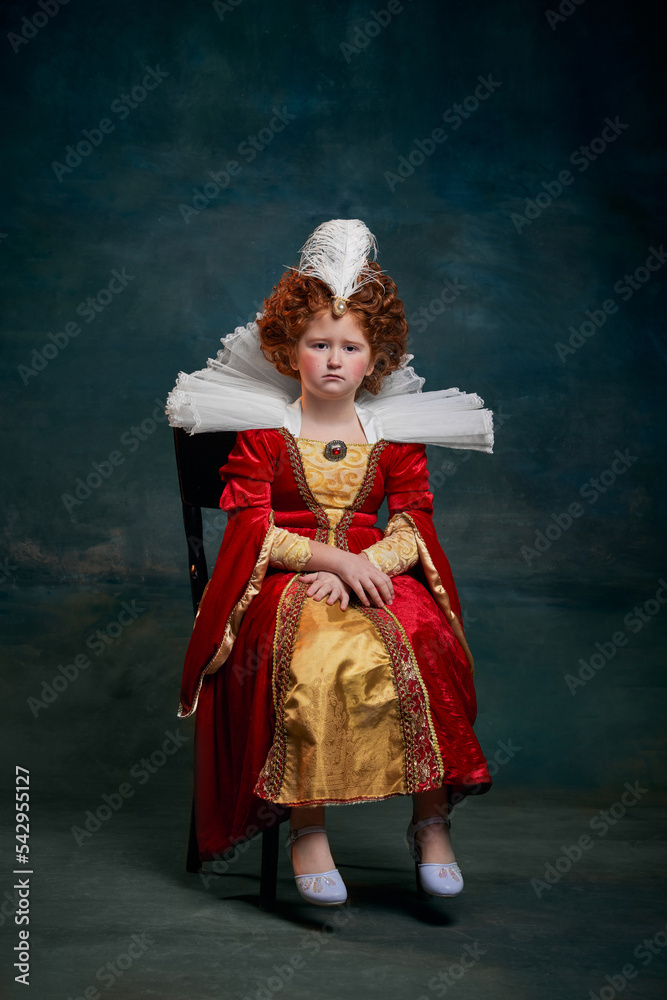 Fototapeta premium Portrait of little red-headed girl, child in costume of royal person isolated over dark green background. Queen Elizabeth I