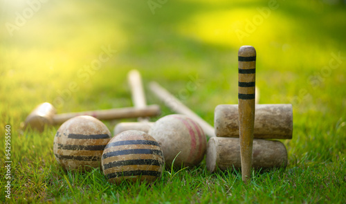 An antique set for playing croquet on the green grass. Wooden clubs with striped balls. Victorian outdoor games. photo