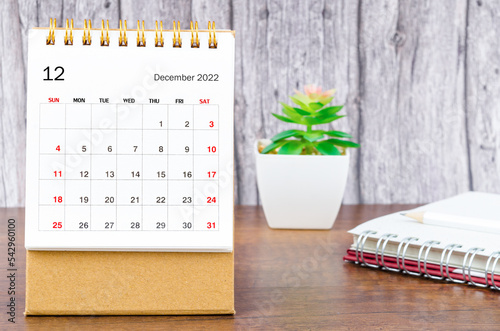 The December 2022 Monthly desk calendar for 2022 year with open diary wooden background. photo