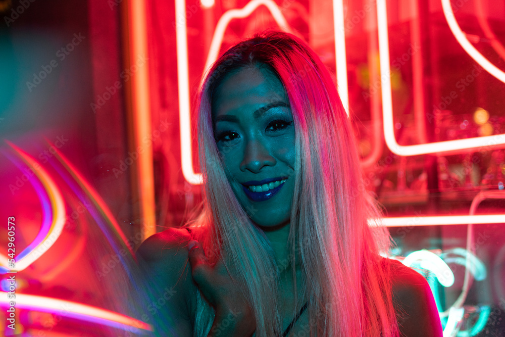 Stylish millennial asian fashion model stand on dark street in neon pink lights Stylish millennial asian fashion model stand on dark street in neon pink lights
