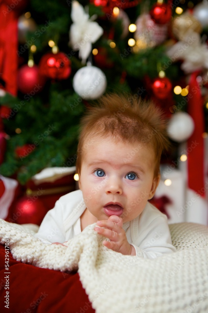 The baby lies in a festive outfit on the background of New Year and Christmas decorations. The concept of holidays for children.