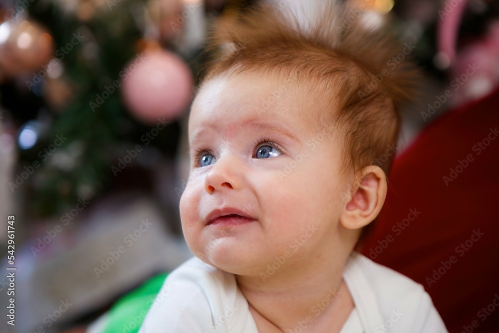 The baby lies in a festive outfit on the background of New Year and Christmas decorations. The concept of holidays for children. The baby lies in a festive outfit on the background of New Year and Christmas decorations. The concept of holidays for children.