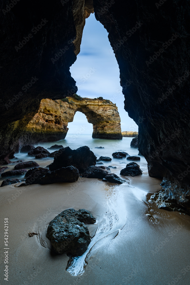 Rocks lying on beach in coastal cave, Algarve