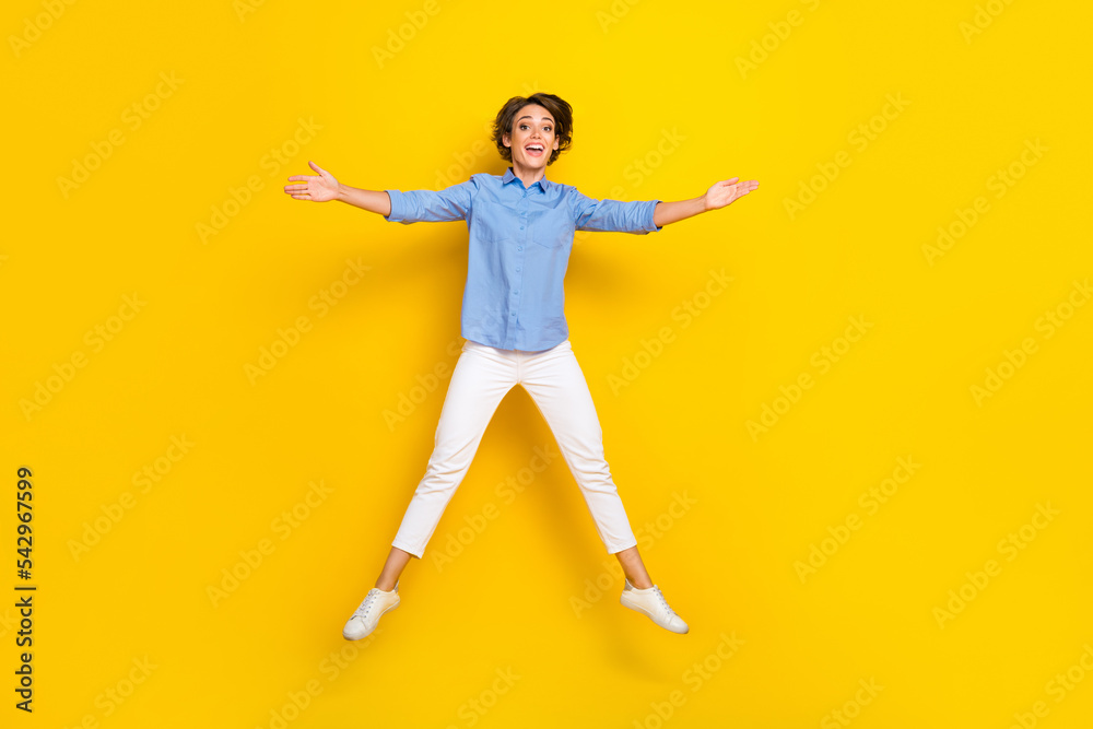 Full length photo of pretty sweet lady wear blue shirt arms jumping high like star isolated yellow color background