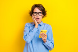 Closeup photo of young impressed young student college information hold phone deadline touch cheeks confused isolated on yellow color background