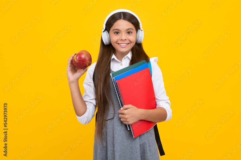School child girl with headphones and book isoalted on yellow background. Happy girl face, positive and smiling emotions. School child girl with headphones and book isoalted on yellow background. Happy girl face, positive and smiling emotions.