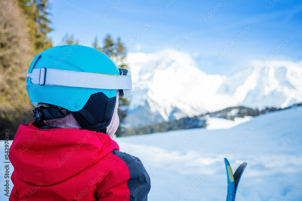 View from behind - girl sit in snow with small mountain ski