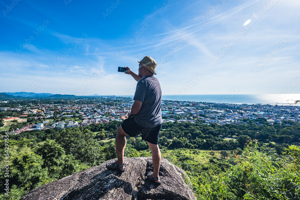 Obraz premium Asian fat man stand on the rock and take photo at Khao hin lek fai view point.Khao Hin Lek Fai is a place to see a spectacular view of the entire town.Also know as khao radar in local people.