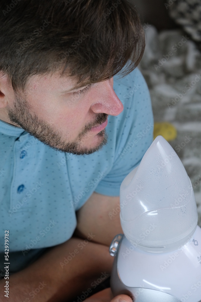 Inhalation and respiration. A man breathes steam to treat his