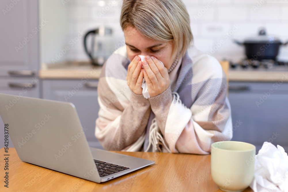 A woman with a short hairdo is sick at home in the kitchen, blowing her nose into a handkerchief. A woman wrapped in a warm scarf is sick and working. A woman with a short hairdo is sick at home in the kitchen, blowing her nose into a handkerchief. A woman wrapped in a warm scarf is sick and working.