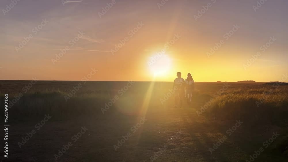 Two boys walking towards the camera with the sunset behind them. Showing sun rays and golden sunset. Two boys walking towards the camera with the sunset behind them. Showing sun rays and golden sunset.
