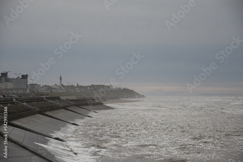 Looking down the coast towards Blackpool tower with waves crashing and a grey sky. Blackpool Lancashire England. 
