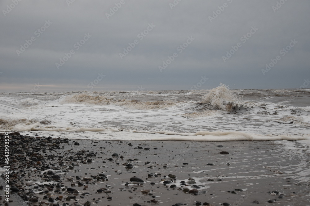 Large waves crashing onto the beach during a storm with a dramatic sky background. Taken in Cleveleys Lancashire England. 