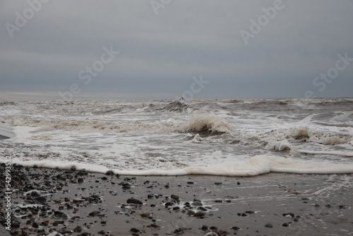 Large waves crashing onto the beach during a storm with a dramatic sky background. Taken in Cleveleys Lancashire England.  photo