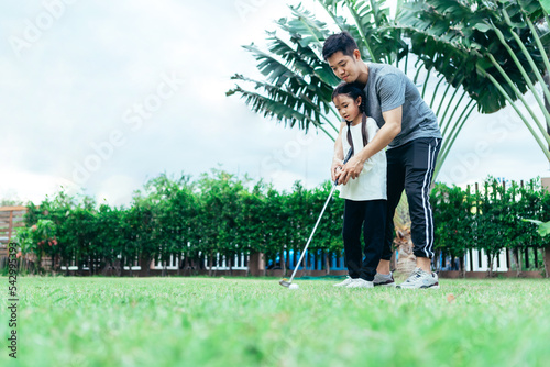 Happy asian family in the garden, Father and doughter. They are having fun playing golf in home garden together