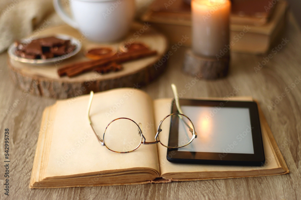 Bowl of cookies, cup of tea or coffee, chocolate, spices, knitted blanket, books, glasses and candle on the table. Cozy hygge atmosphere at home. Selective focus. Bowl of cookies, cup of tea or coffee, chocolate, spices, knitted blanket, books, glasses and candle on the table. Cozy hygge atmosphere at home. Selective focus.