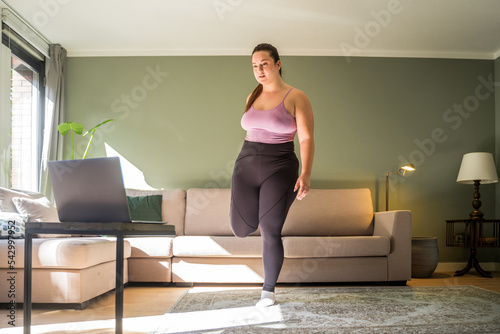 Body positive woman spending time in home while training and stretching legs