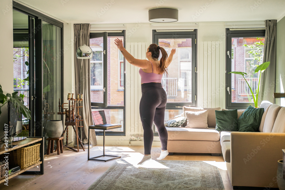Young overweight woman exercising and jumping alone at home Young overweight woman exercising and jumping alone at home