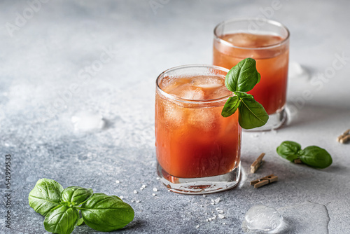 Tomato juice or Bloody Mary iced cocktail with bazil leaves in two glasses for drink menu on blue textured background with text space photo