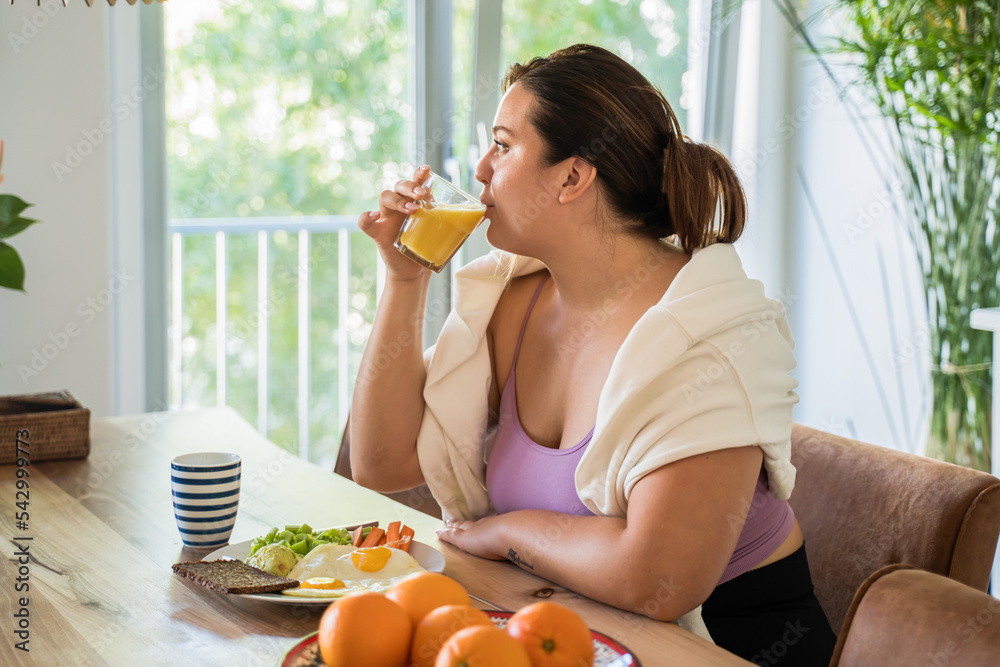 Brunette woman drinking juice and looking at the window while eating tasty food Brunette woman drinking juice and looking at the window while eating tasty food