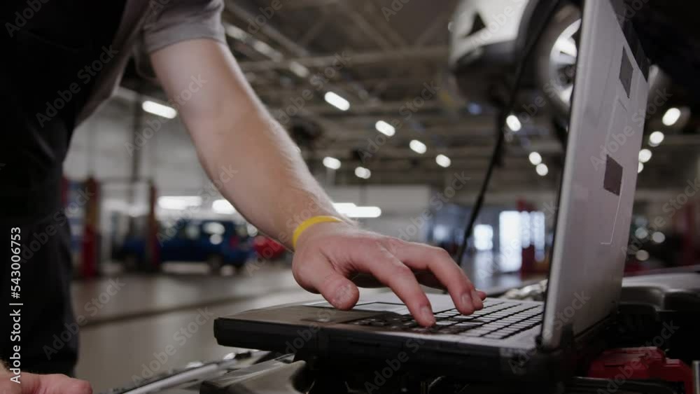 Close-up of a diagnostic laptop on which an auto mechanic works against the background of a service center Close-up of a diagnostic laptop on which an auto mechanic works against the background of a service center