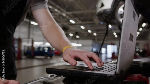 Close-up of a diagnostic laptop on which an auto mechanic works against the background of a service center