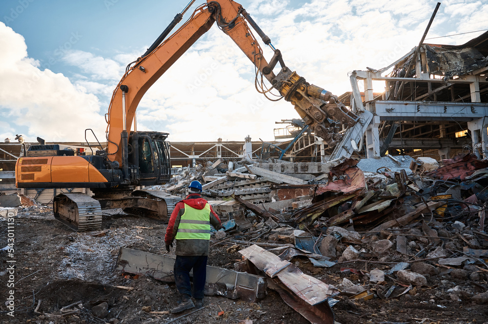 Fototapeta premium Excavator destroyer removes debris under worker control