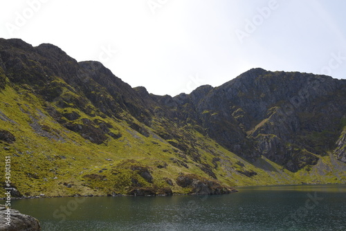 a view looing down in the crater of Cadair Idris with a mountain view behind it photo