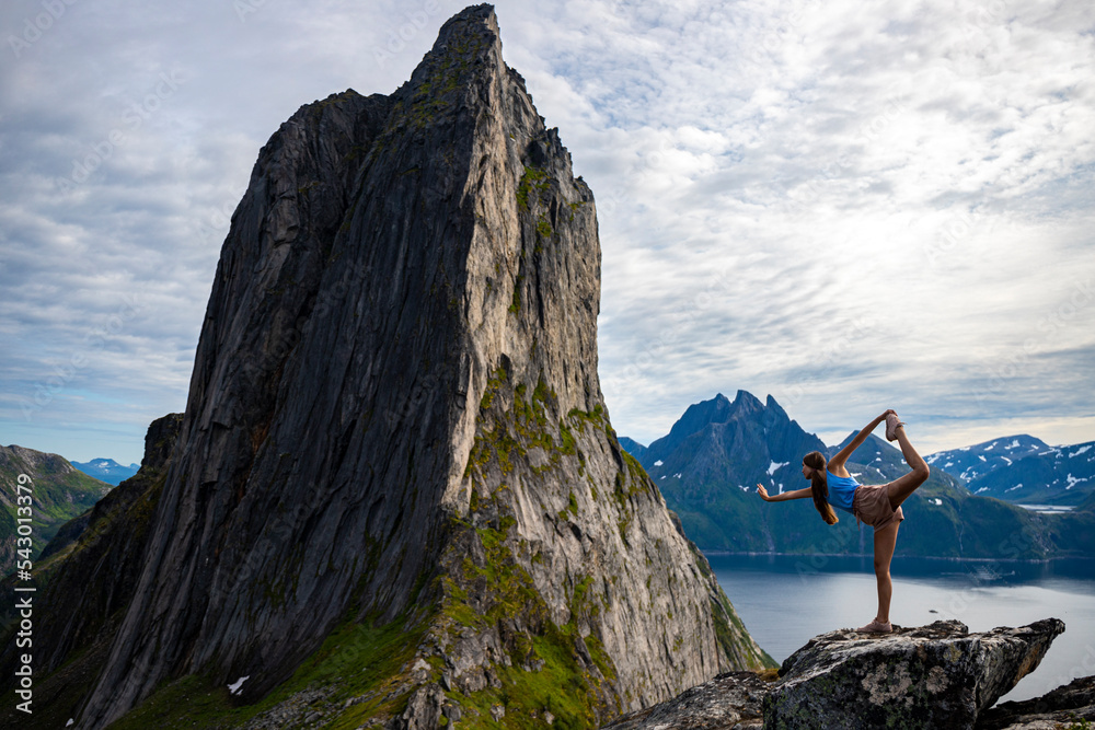 backpacker girl stretches (yoga - dancer position) on the rocks