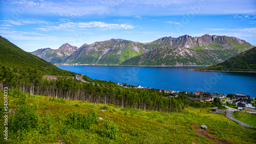 view from the hesten trailhead of the town of fjordegard and the mighty mountains in the norwegian fjord on the island of senja