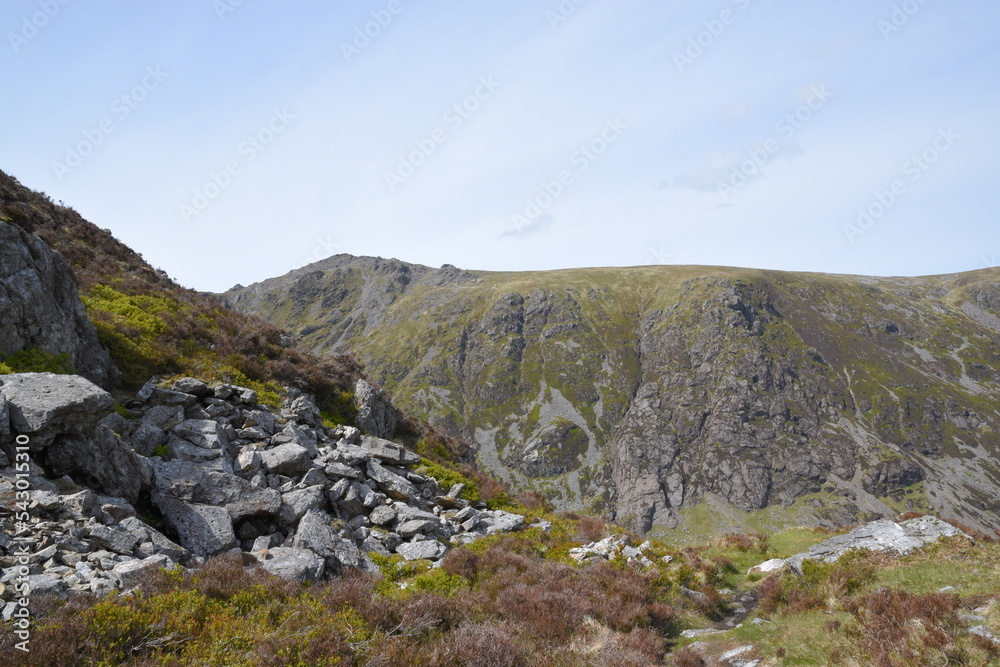 a view looing down in the crater of Cadair Idris with a mountain view behind it