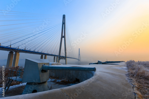 Russian bridge in Vladivostok in winter. View of the Russian bridge from the Novosiltsevskaya battery at dawn. photo