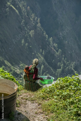 Vertical shot of a female traveller with her baby on her back in Rasol Village of Himachal Pradesh photo