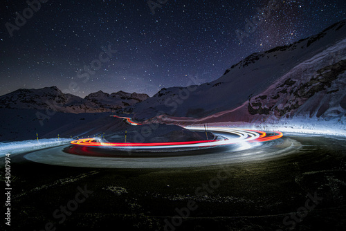 A car doing a turn in the mountain.  Stars shine bright at night. Long exposure shot.