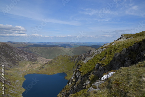 a view looing down in the crater of Cadair Idris with a mountain view behind it