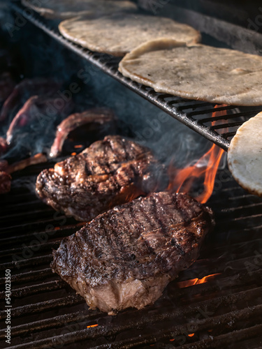 Juicy Ribeye steaks cooking on barbecue grill