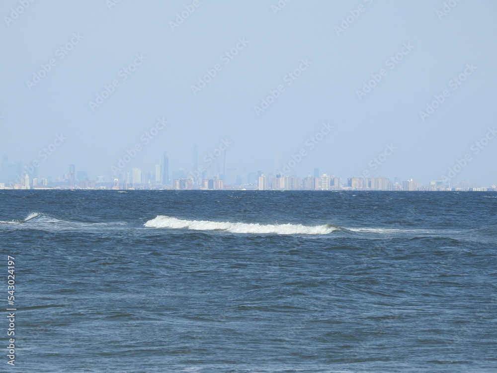 Waves gently rolling over the Atlantic Ocean with New York City in the far distant background.