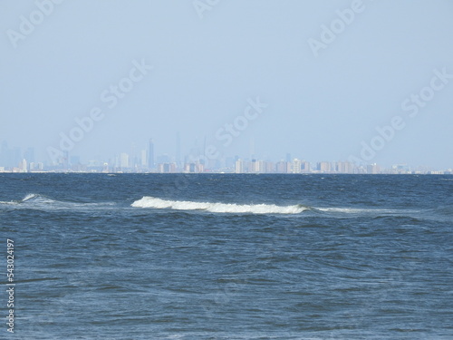 Waves gently rolling over the Atlantic Ocean with New York City in the far distant background.