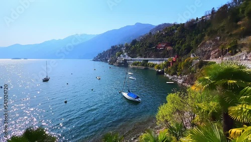 The sparkling ripples on Lake Maggiore surface with moored yachts, boats and hazy Alps in background, Ascona, Switzerland photo